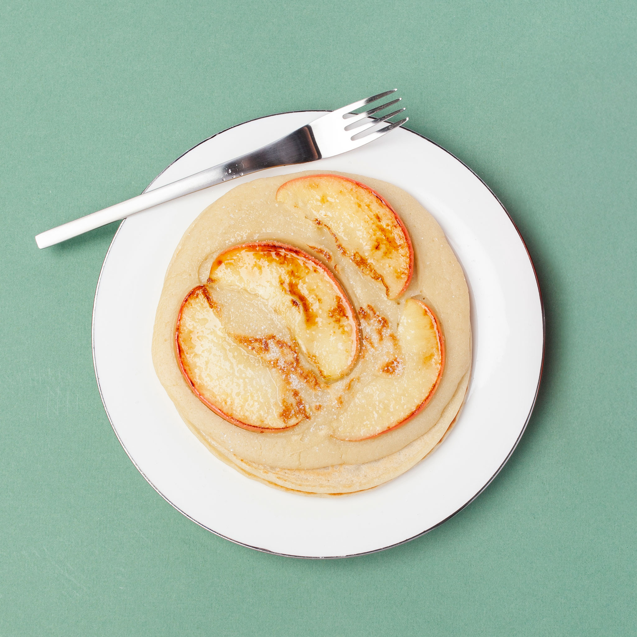 Apfel-Pfannkuchen auf einem Teller mit einer Gabel dazu