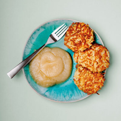 Reibe-Kuchen auf einem Teller mit einem Schlag Apfelkompott