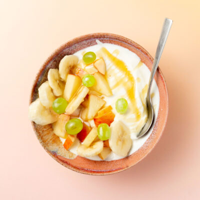 Obst-Salat mit Joghurt, angerichtet in einer roten Schale