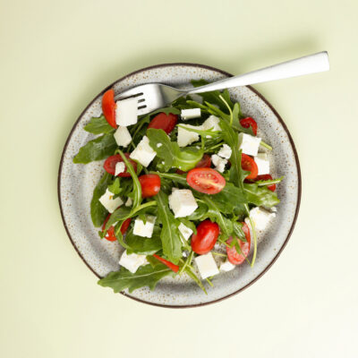 Eine Portion Rucola Salat angerichtet auf einem Teller mit grünem Hintergrund