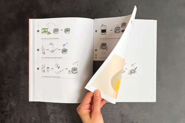 Eine Hand blättert in dem Kochbuch in Leichter Sprache von Leichtes Kochen